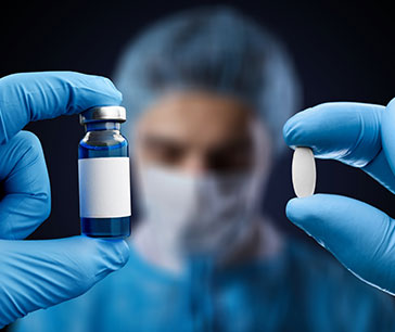 A doctor holding a vaccine vial in one hand and a tablet in the other